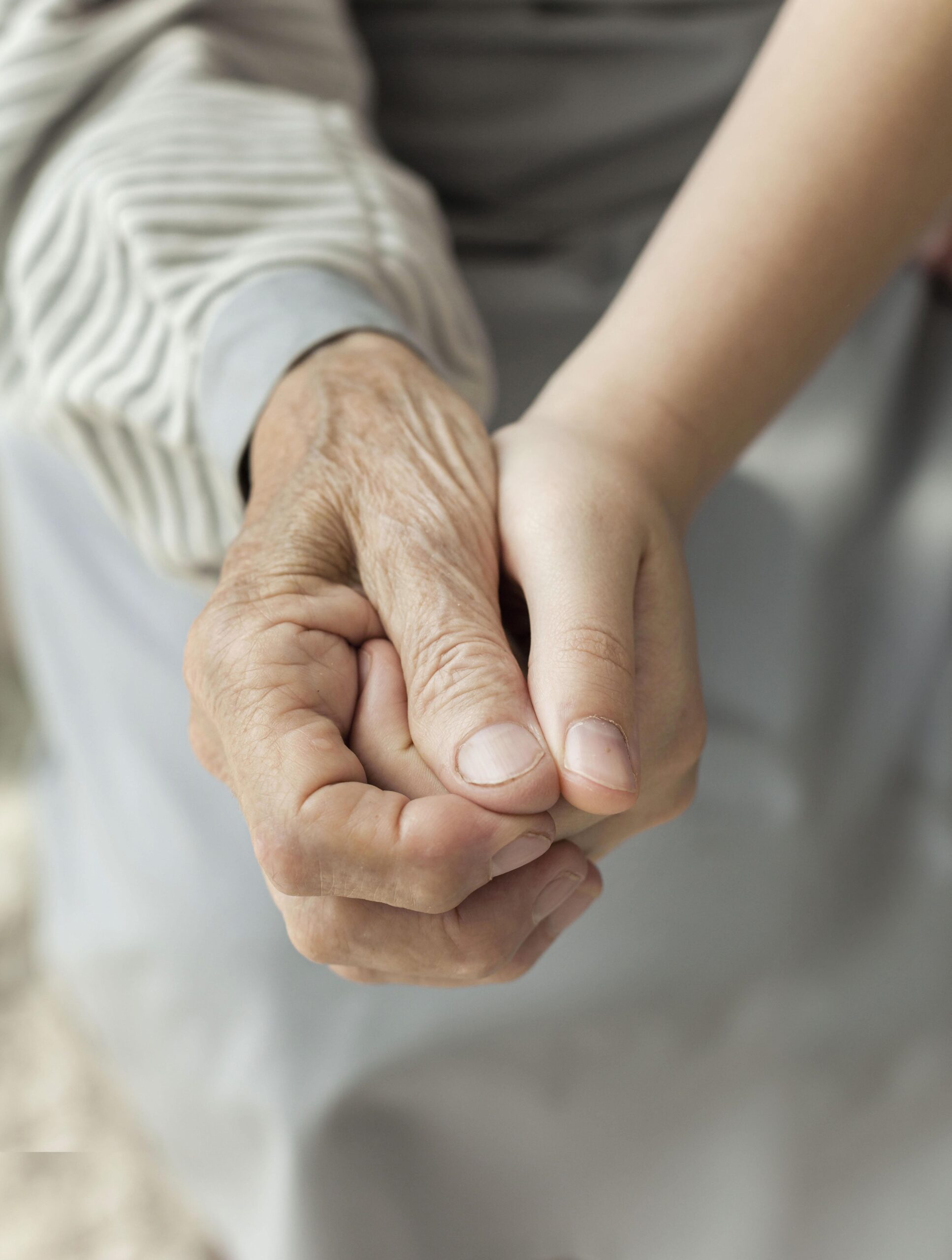 Eine junge Hand hält die Hand einer älteren Person.
